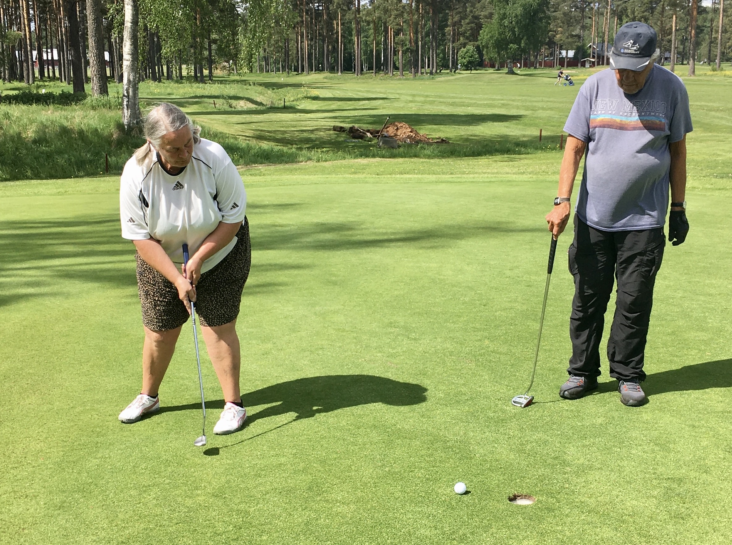 Ewa Karles puttar på hål 14 under överinseende av Lars Landstedt.